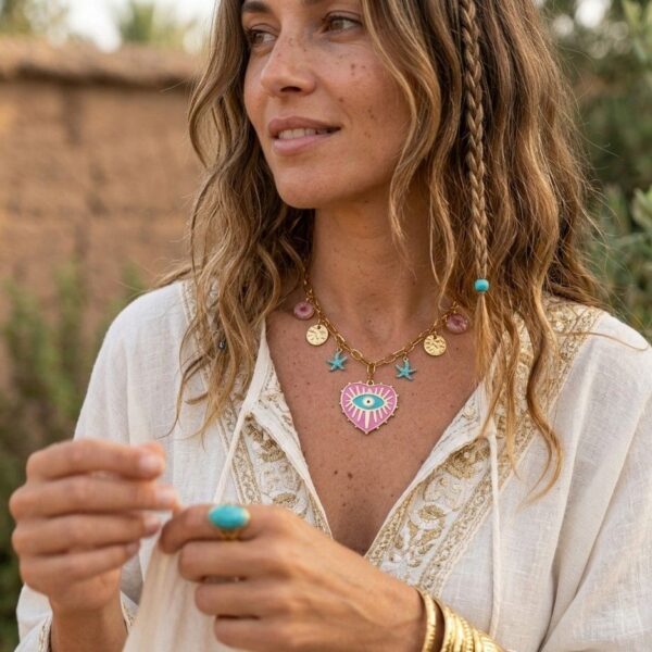 Succombez au charme méditerranéen avec le collier Milos. Une chaîne dorée ornée d'un cœur protecteur et de breloques marines pour un style bohème irrésistible.