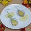 Appoline Boucles d'oreilles graphiques et dépareillées au jaune solaire, mêlant finesse ajourée et motifs floraux délicats.