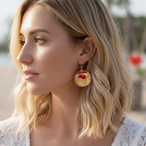 Boucles d'oreilles Cléa portées, modèle cerise rouge en tissu washi japonais et cercles dorés légers.