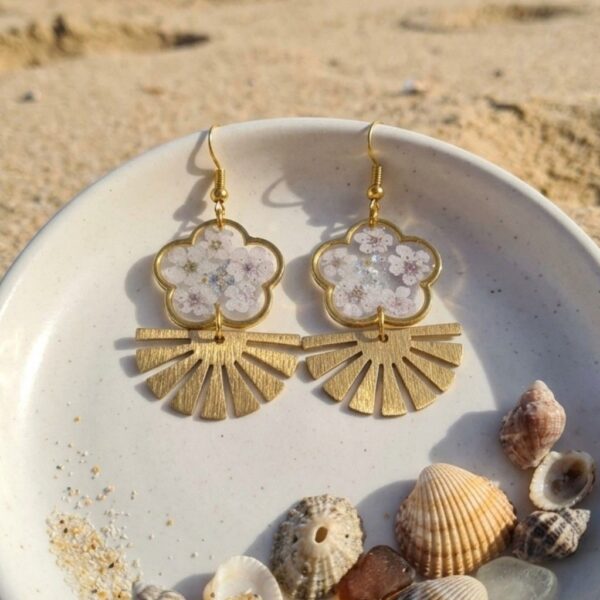 Détail des Daniela Boucles Blanches Papillons avec pétales de fleurs séchées, paillettes dorées et résine artisanale.