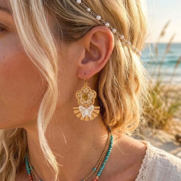 Détail des Daniela Boucles Blanches Papillons avec pétales de fleurs séchées, paillettes dorées et résine artisanale.