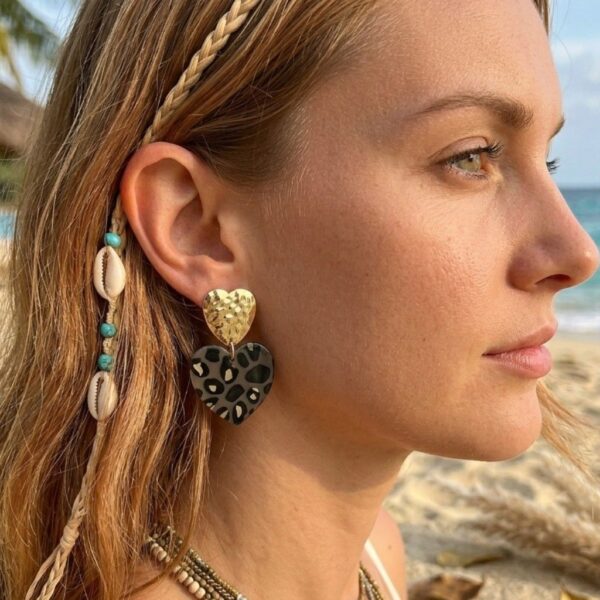 Femme portant les boucles d'oreilles Eden cœurs léopard pour un look bohème chic et moderne.