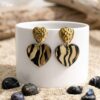 Élisa Boucles Cœurs Zébré motif zébré calligraphié à la main, finition résine brillante et poussoirs cœurs martelés en acier doré."