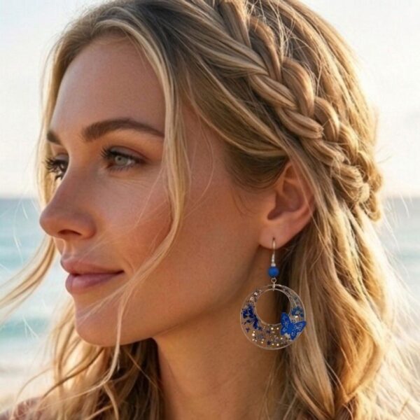 Détail breloque résine avec papillons, fleurs bleues et paillettes argentées.