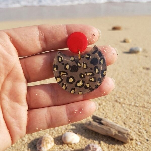 Détail du fermoir rond émaillé rouge et du motif léopard résiné, bijou artisanal français hypoallergénique.