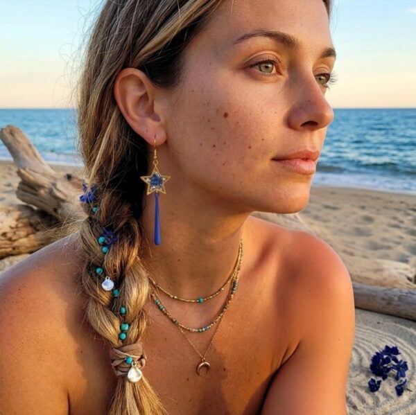 Gros plan sur les boucles d'oreilles célestes Ophélie, montrant la longueur élégante et l'éclat des fleurs séchées bleu marine sur l'oreille."