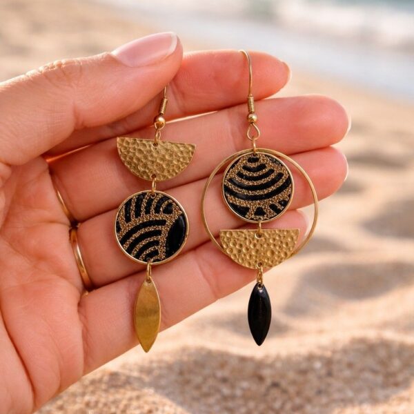 "Gros plan des boucles asymétriques Yuna portées, mettant en valeur le contraste chic du tissu noir et de l'or sur l'oreille."