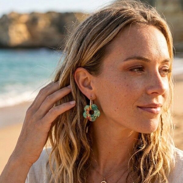 Portrait rapproché d'une personne portant une créole dorée Flavy avec le pendentif fleur, côté papier Washi motif floral visible. Le bijou est léger et élégant.