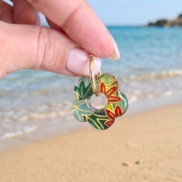 Gros plan d'une paire de boucles d'oreilles créoles dorées avec des pendentifs fleurs en papier Washi motif japonais,