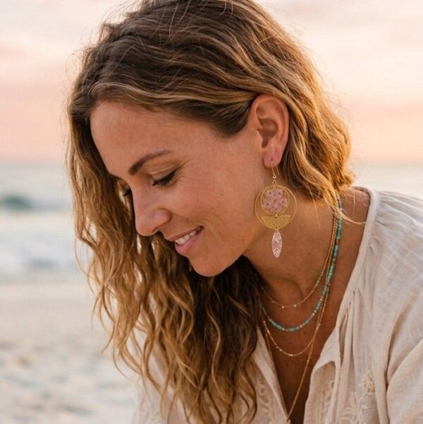 "Mise en situation des boucles d'oreilles Himari portées, révélant leur superbe asymétrie et l'éclat lumineux des fleurs séchées roses sur l'oreille."