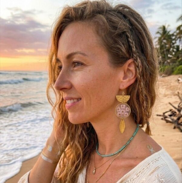 "Mise en situation des boucles d'oreilles Himari portées, révélant leur superbe asymétrie et l'éclat lumineux des fleurs séchées roses sur l'oreille."