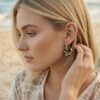 Créoles fleurs Capucine côté zébré portée par une femme sur une plage