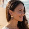 Boucles d'oreilles fleur léopard Clémence portée à l'oreille par une femme style bohème sur la plage