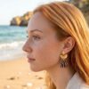 Boucles d'oreilles fleur zébré Clémence portée à l'oreille par une femme style bohème sur la plage