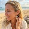 Boucle d'oreille asymethrique Denise portée par une femme blonde sur une plage