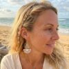 Boucle d'oreille asymethrique Denise portée par une femme blonde sur une plage