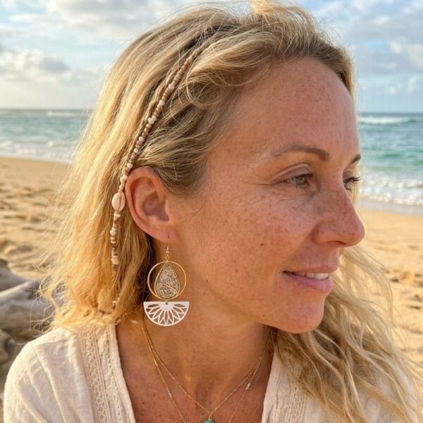 Boucle d'oreille asymethrique Denise portée par une femme blonde sur une plage