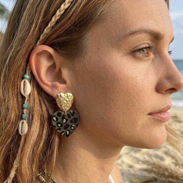 Femme portant les boucles d'oreilles Eden cœurs léopard pour un look bohème chic et moderne.