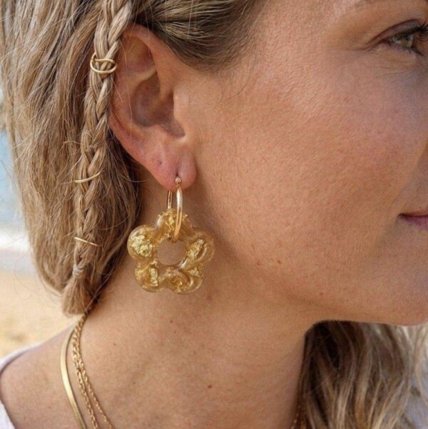 Créoles fleurs Capucine côté nacré doré portée par une femme sur une plage
