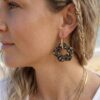 Créoles fleurs Capucine côté léopard portée par une femme sur une plage