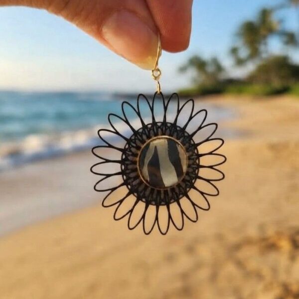 Gros plan sur les boucles d'oreilles Garance fleurs noires papier calligraphié zébré et acier inoxydable or